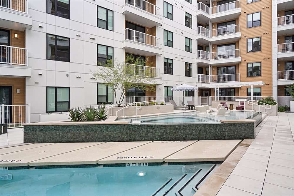 Contemporary apartment building with outdoor pool and lounge area.
