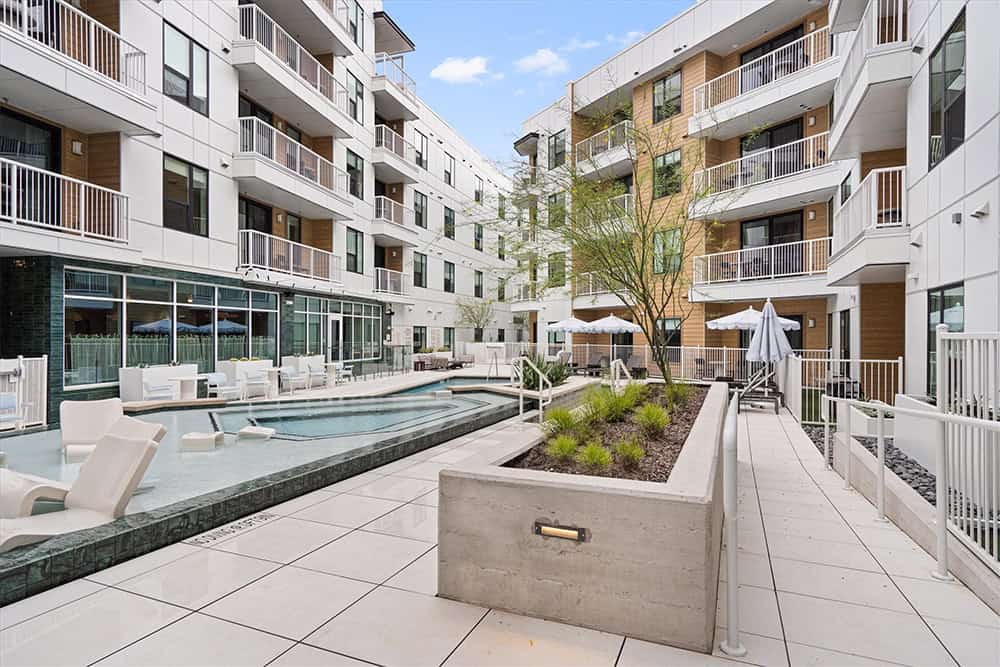 Contemporary apartment complex with outdoor pool and lounge area.