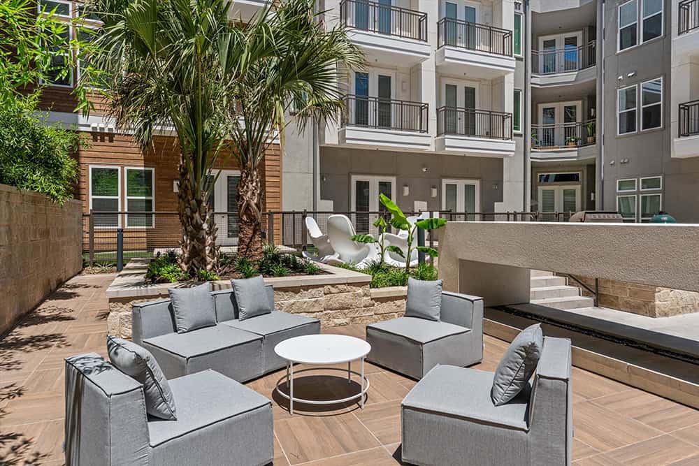 Outdoor seating area with sofas and palm trees in apartment courtyard.