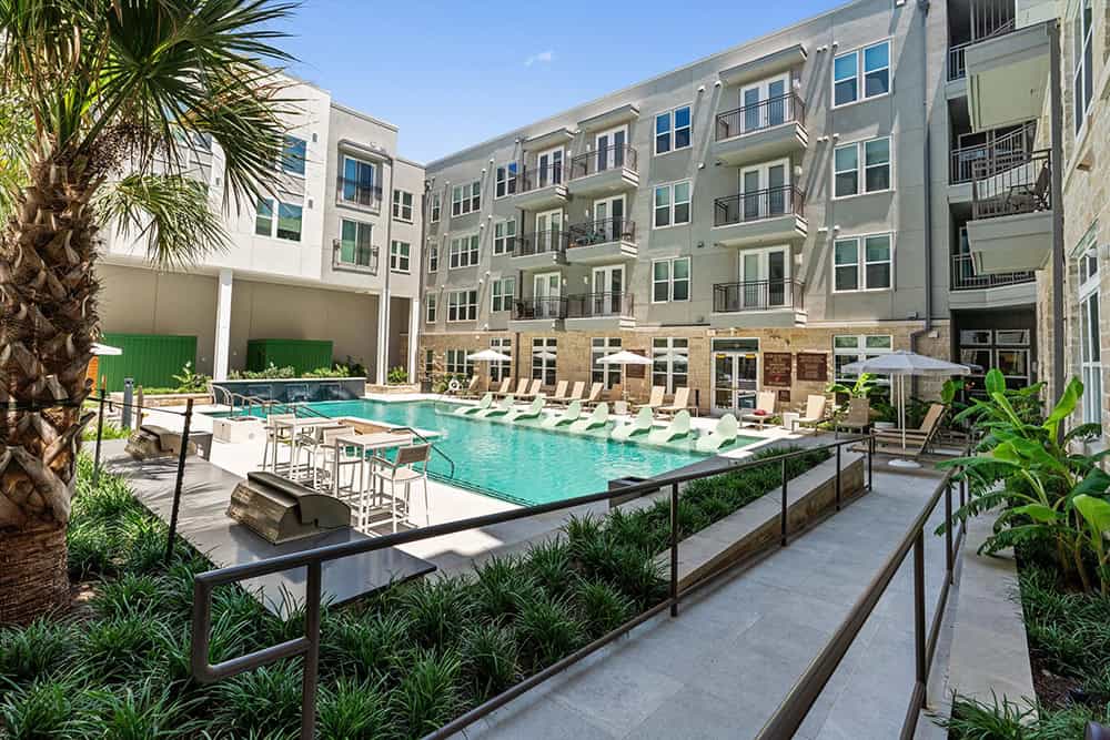 Contemporary apartment building with outdoor pool and lounge area.